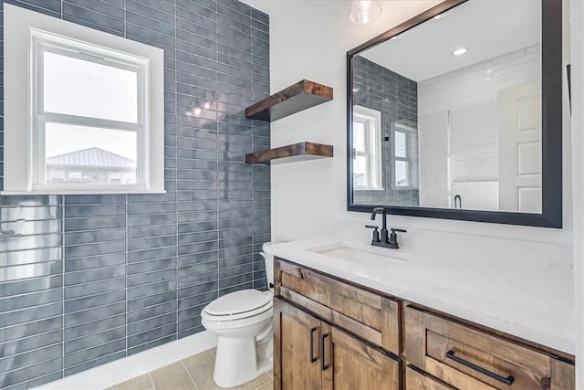 bathroom with vanity, tile patterned floors, toilet, and a healthy amount of sunlight