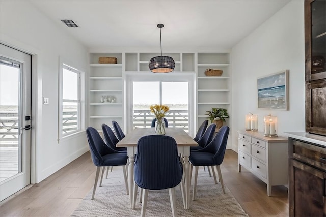 dining room featuring light wood-type flooring and built in shelves