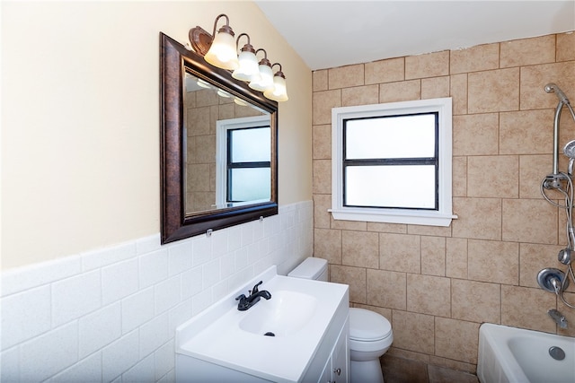 bathroom featuring a tub, vanity, toilet, and tile walls