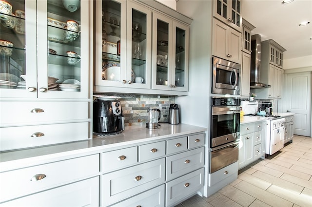 kitchen with stainless steel appliances, white cabinets, wall chimney exhaust hood, tasteful backsplash, and gray cabinetry