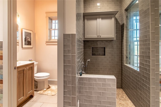 bathroom with toilet, vanity, tile patterned flooring, and a tile shower