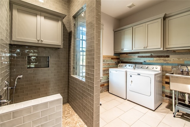 washroom featuring washing machine and dryer, cabinets, sink, and light tile patterned floors