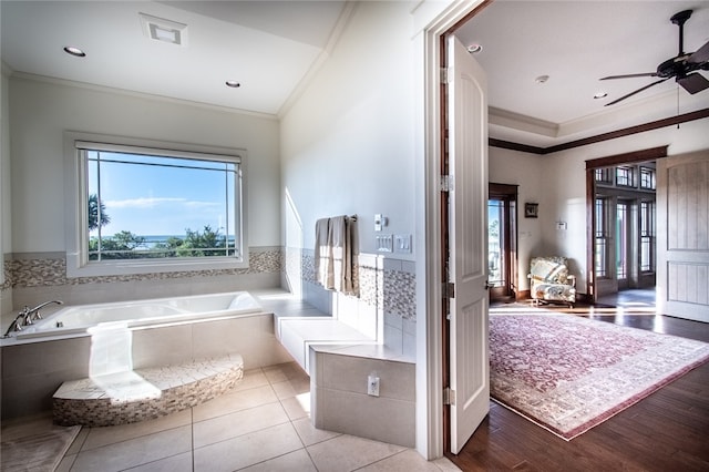 bathroom with hardwood / wood-style floors, tiled bath, ceiling fan, and crown molding