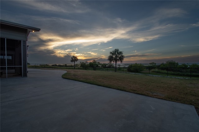 patio terrace at dusk featuring a yard