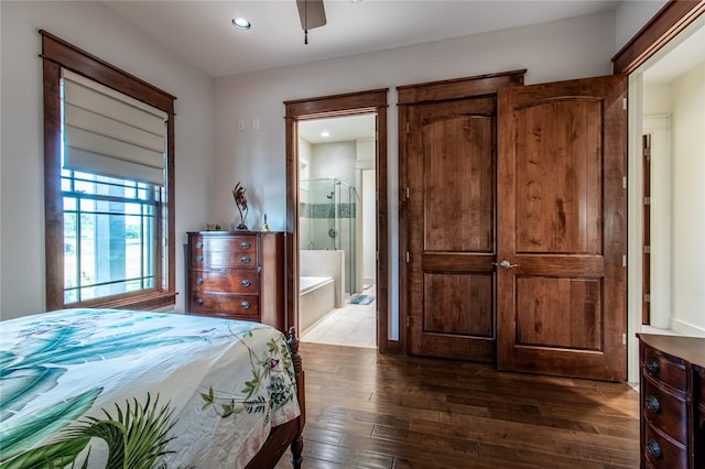 bedroom featuring dark wood-type flooring, ceiling fan, connected bathroom, and a barn door