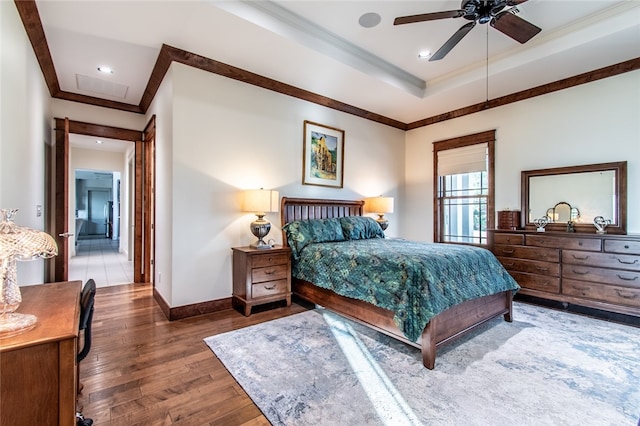 bedroom with dark hardwood / wood-style flooring, ornamental molding, a tray ceiling, and ceiling fan