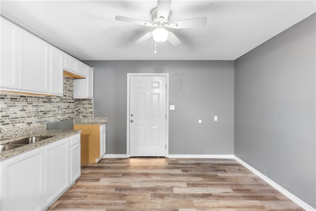 kitchen featuring white cabinets, decorative backsplash, ceiling fan, and light wood-type flooring