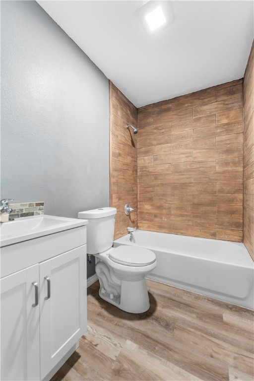 full bathroom featuring hardwood / wood-style flooring, vanity, toilet, and tiled shower / bath