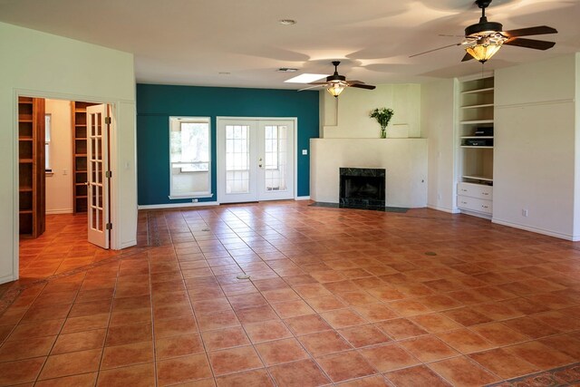 unfurnished living room featuring french doors, built in features, ceiling fan, and tile patterned flooring