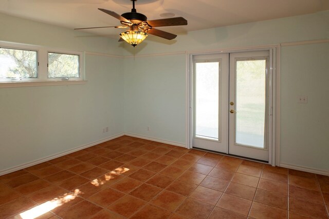 tiled empty room featuring french doors and ceiling fan