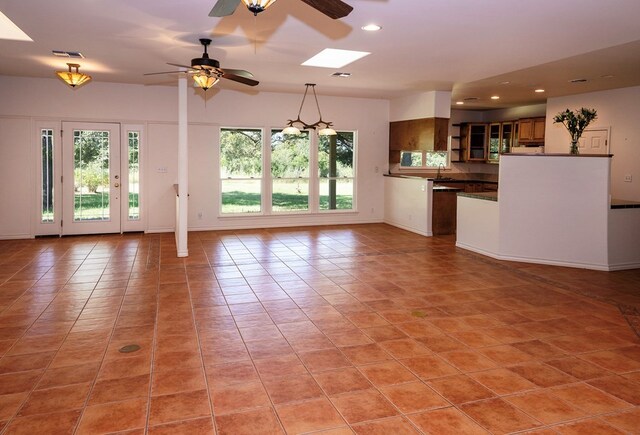 kitchen featuring ceiling fan, a skylight, light tile patterned flooring, and plenty of natural light