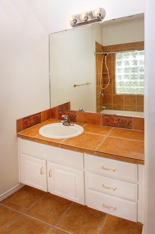 bathroom featuring tiled shower / bath, vanity, and tile patterned floors