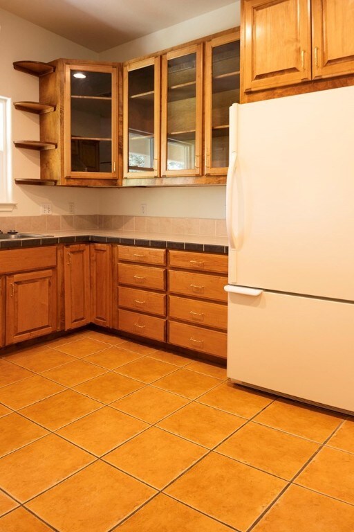 kitchen with tile countertops, light tile patterned flooring, and white fridge