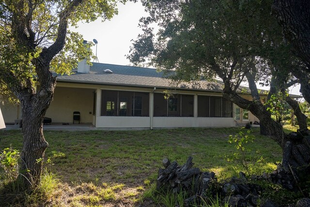 rear view of house featuring a sunroom and a yard