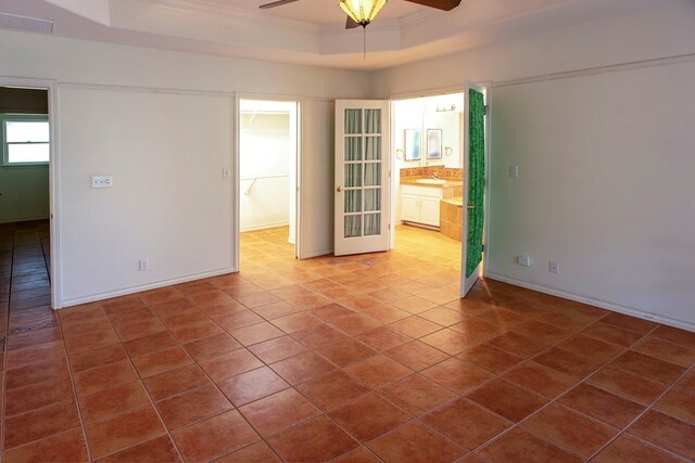 empty room with sink, ceiling fan, a tray ceiling, crown molding, and dark tile patterned flooring