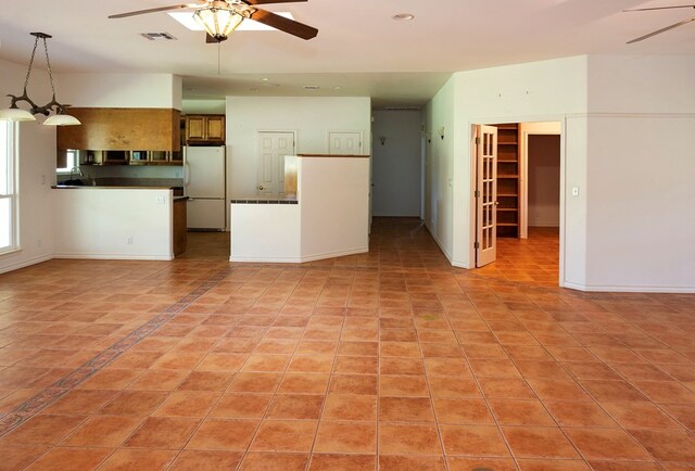 interior space with pendant lighting, ceiling fan, light tile patterned floors, and white refrigerator