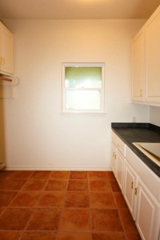 clothes washing area with dark tile patterned floors and sink