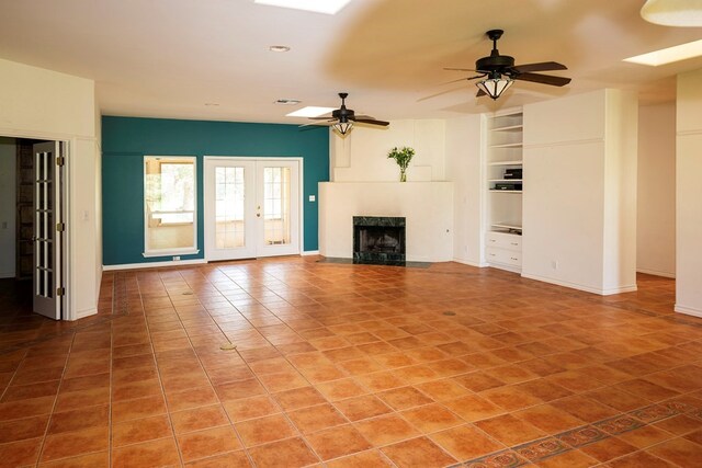 unfurnished living room with built in features, ceiling fan, and tile patterned floors