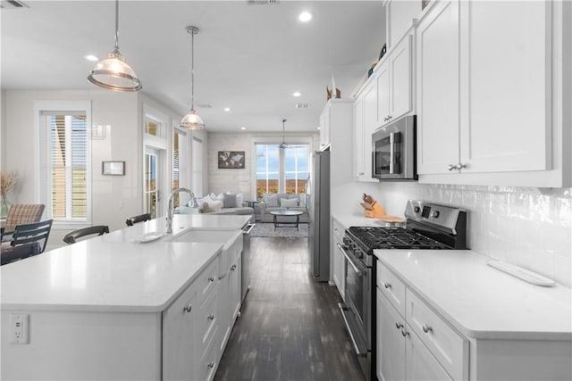 125 Fish Hook Ln, Port Aransas, TX 78373 - kitchen featuring white cabinets, dark wood finished floors, a center island with sink, appliances with stainless steel finishes, and open floor plan