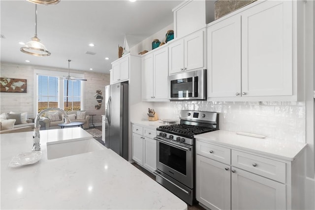 125 Fish Hook Ln, Port Aransas, TX 78373 - kitchen with a sink, open floor plan, pendant lighting, stainless steel appliances, and white cabinets