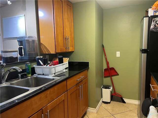 kitchen featuring light tile patterned floors, brown cabinets, and a sink