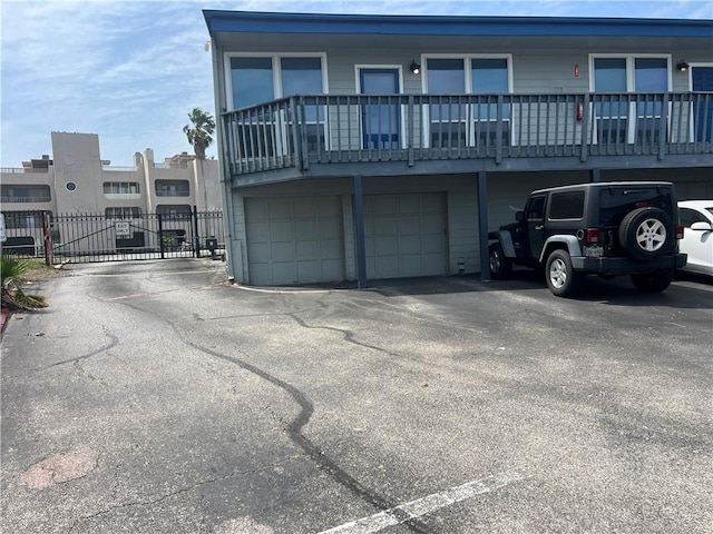 rear view of property featuring aphalt driveway, a garage, and a gate