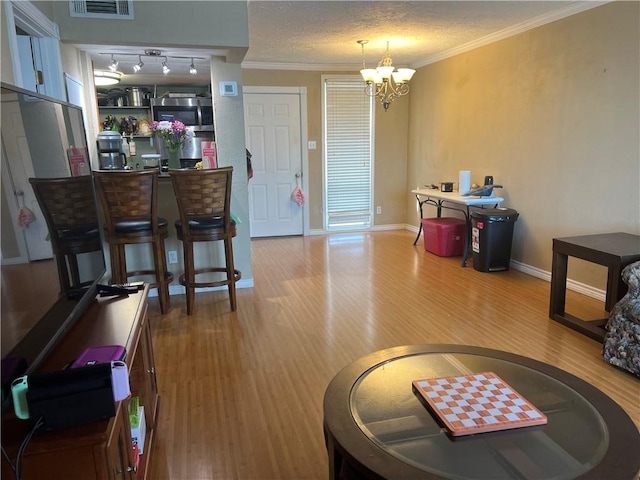 interior space featuring wood finished floors, baseboards, a textured ceiling, crown molding, and a notable chandelier