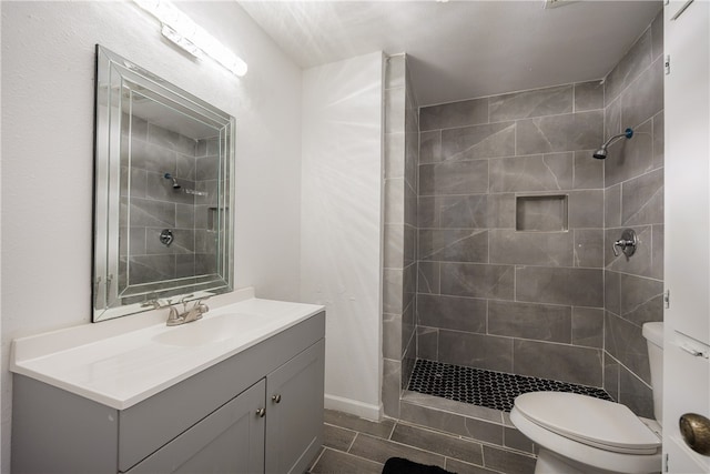 bathroom with vanity, toilet, and tiled shower