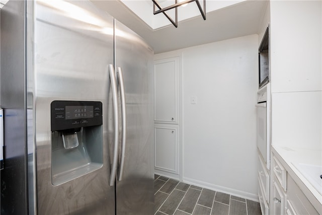 kitchen featuring stainless steel fridge, dark hardwood / wood-style flooring, white cabinetry, and white oven