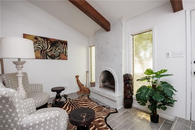 sitting room featuring a tile fireplace and lofted ceiling with beams