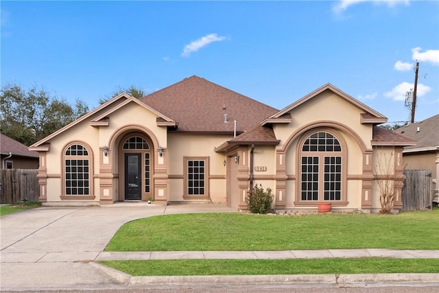 view of front facade featuring a front lawn, a shingled roof, fence, and stucco siding