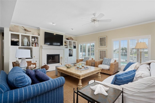 living room with a tiled fireplace, hardwood / wood-style flooring, ornamental molding, and ceiling fan