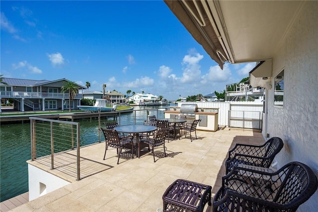 view of patio / terrace featuring grilling area, an outdoor kitchen, and a water view