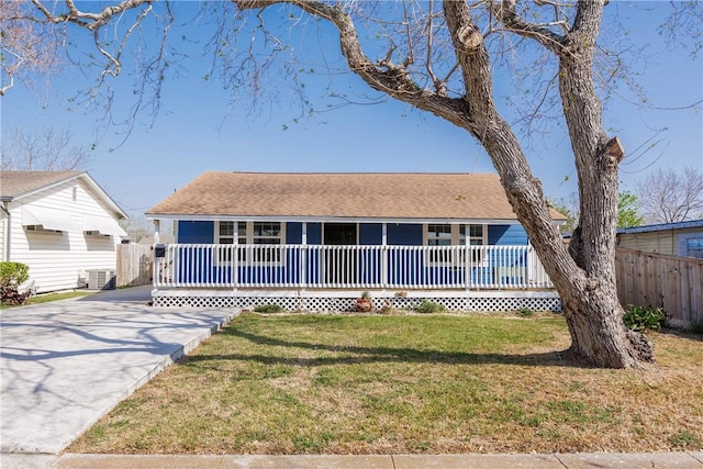 ranch-style home featuring a front lawn, fence, covered porch, cooling unit, and driveway