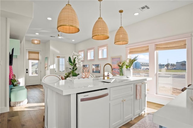 kitchen featuring white dishwasher, visible vents, a sink, and wood finished floors