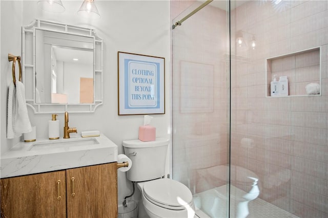full bath featuring toilet, tiled shower, and vanity