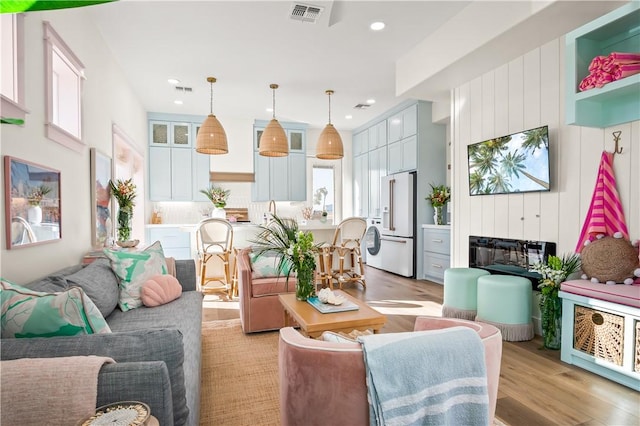 living area with light wood-type flooring, visible vents, and recessed lighting