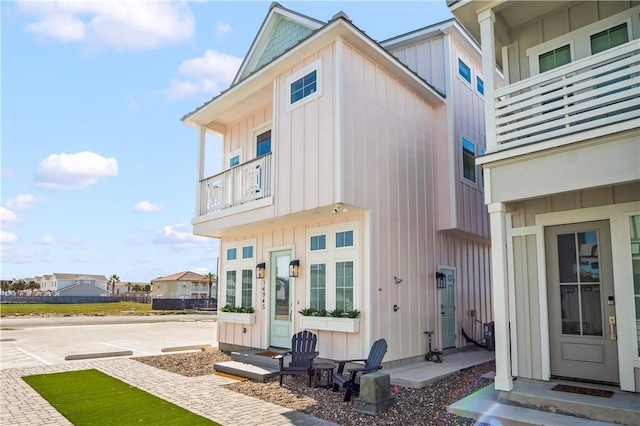 back of house featuring board and batten siding, entry steps, and a balcony