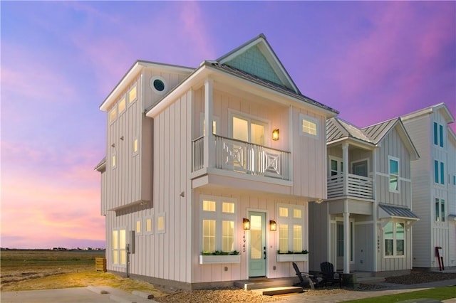 view of front facade with a standing seam roof, metal roof, board and batten siding, and a balcony