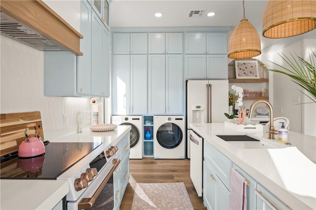 kitchen with white appliances, visible vents, custom range hood, separate washer and dryer, and a sink
