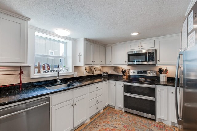 kitchen with a textured ceiling, white cabinets, sink, and stainless steel appliances