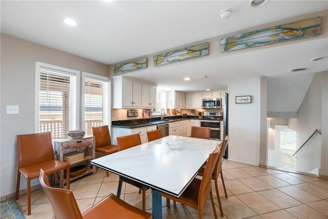 kitchen with appliances with stainless steel finishes, sink, light tile patterned flooring, and white cabinets