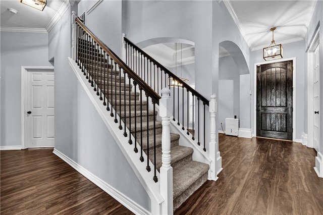 entrance foyer featuring dark wood-type flooring, a notable chandelier, and ornamental molding