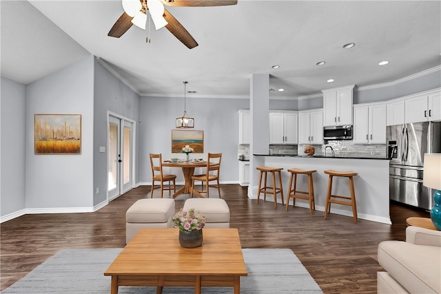 living room with dark hardwood / wood-style floors, ceiling fan with notable chandelier, sink, and crown molding