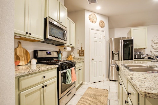 kitchen featuring light stone counters, a sink, visible vents, stainless steel appliances, and light tile patterned flooring