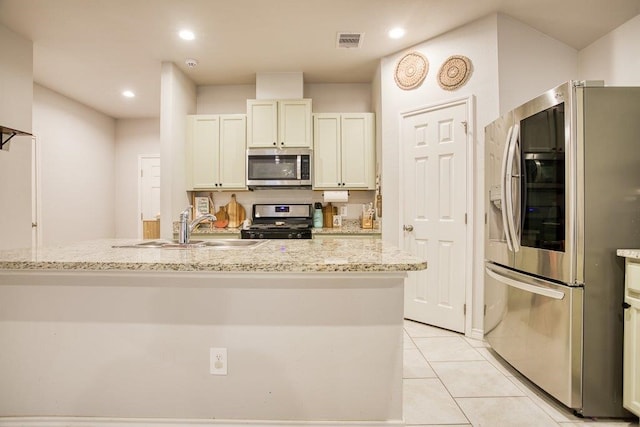 kitchen with light stone countertops, a sink, stainless steel appliances, light tile patterned flooring, and visible vents