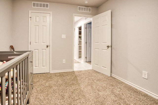 unfurnished bedroom with baseboards, visible vents, and light carpet