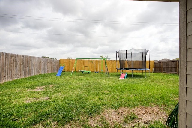 view of yard with a trampoline, a playground, and a fenced backyard