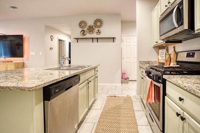 kitchen with a kitchen island with sink, a sink, light tile patterned flooring, visible vents, and appliances with stainless steel finishes