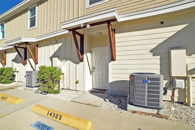 property entrance featuring central AC unit and board and batten siding